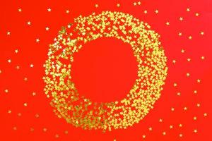 toile de fond rouge avec des confettis de paillettes et d'étoiles dorées en cercle. fond clair de vacances festives photo