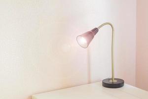 lampe de bureau avec lumière allumée sur une table blanche, concept de lieu de travail indépendant photo