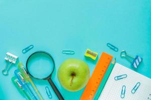 concept de retour à l'école - fournitures de bureau scolaires sur fond bleu. copiez l'espace pour votre conception photo