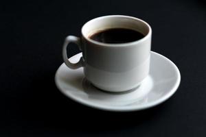 gros plan d'une tasse de café blanche sur fond noir. mise au point douce photo