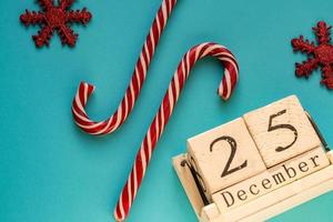 calendrier en bloc de bois indiquant le 25 décembre. vacances de Noël. carte de voeux avec des cannes de bonbon et des flocons de neige étincelants. photo