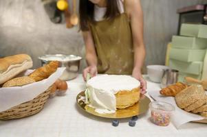 gros plan sur une belle jeune femme cuit dans sa cuisine, sa boulangerie et son café photo