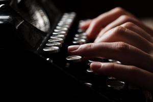 Mains écrivant sur une vieille machine à écrire sur fond de bois photo