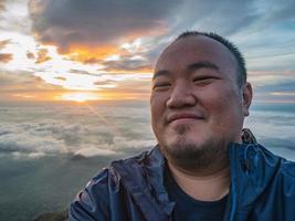 voyageur asiatique prendre un selfie avec un beau ciel de lever de soleil sur la montagne photo