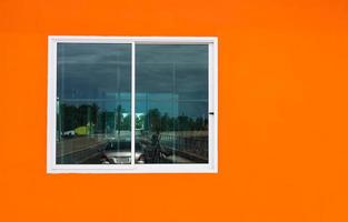 le fond de mur en béton orange du bâtiment et les fenêtres blanches avec du verre transparent se reflètent. photo