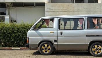 une vue rapprochée d'une vieille camionnette grise garée près du côté d'un immeuble de bureaux thaïlandais. photo