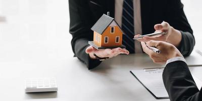 agent de courtage immobilier présentant et consultant au client pour la prise de décision signant un accord de formulaire d'assurance, modèle de maison, concernant l'offre de prêt hypothécaire et l'assurance habitation.