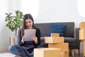 portrait d'une jeune femme asiatique sme travaillant avec une boîte à la maison le lieu de travail. propriétaire de petite entreprise de démarrage, entrepreneur de petite entreprise sme ou entreprise indépendante en ligne et concept de livraison. photo