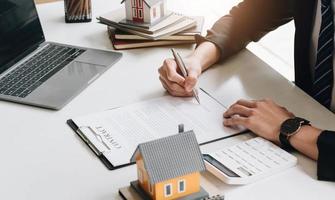 entreprise signant un contrat d'achat - vente de maison, concept de maison à louer, agent de courtage présentant et consultant les détails au client pour prendre la décision d'un prêt immobilier au client signant un formulaire d'accord. photo