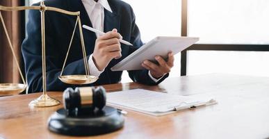 concept de droit et de services juridiques, bonne coopération de service, mains d'avocat utilisant une tablette et travaillant sur un bureau de table en bois. photo