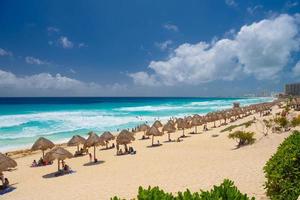 parapluies sur une plage de sable avec de l'eau azur par une journée ensoleillée près de cancun, mexique photo