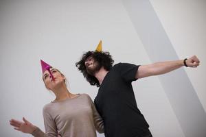 couple en chapeaux de fête soufflant dans un sifflet photo