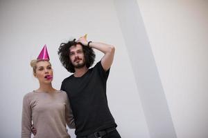 couple en chapeaux de fête soufflant dans un sifflet photo