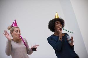 femmes souriantes en casquettes de fête soufflant aux sifflets photo