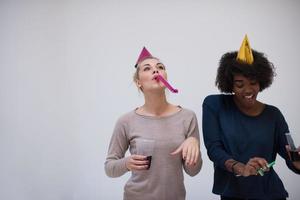 femmes souriantes en casquettes de fête soufflant aux sifflets photo