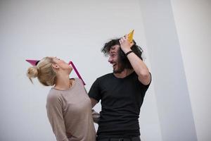 couple en chapeaux de fête soufflant dans un sifflet photo