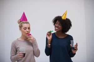 femmes souriantes en casquettes de fête soufflant aux sifflets photo