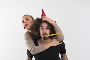 couple en chapeaux de fête soufflant dans un sifflet photo