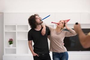 couple en chapeaux de fête soufflant dans un sifflet photo