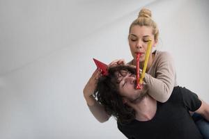 couple en chapeaux de fête soufflant dans un sifflet photo