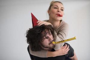 couple en chapeaux de fête soufflant dans un sifflet photo