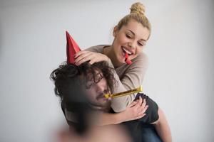 couple en chapeaux de fête soufflant dans un sifflet photo