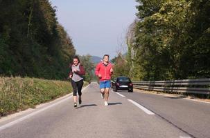 jeune couple faisant du jogging le long d'une route de campagne photo