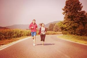 jeune couple faisant du jogging le long d'une route de campagne photo