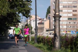 jeune couple multiethnique souriant faisant du jogging dans la ville photo