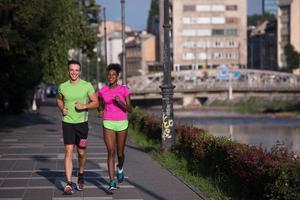 jeune couple multiethnique souriant faisant du jogging dans la ville photo