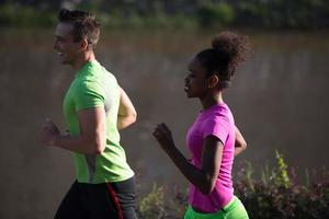 jeune couple multiethnique souriant faisant du jogging dans la ville photo