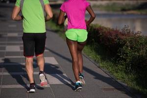 jeune couple multiethnique souriant faisant du jogging dans la ville photo