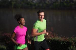 jeune couple multiethnique souriant faisant du jogging dans la ville photo