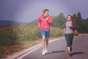 jeune couple faisant du jogging le long d'une route de campagne photo