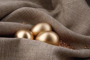 trois œufs d'or sont enveloppés dans du tissu. photo