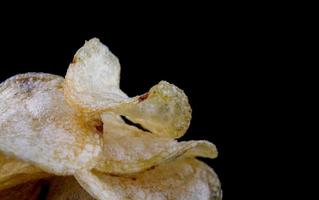 croustilles sur fond noir. chips de pommes de terre croustillantes. photo