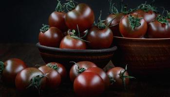 beaucoup de tomates juteuses mûres sur fond noir. tomates cerises. photo