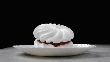 deux meringues blanches comme neige sur une assiette blanche. beau gâteau blanc. photo