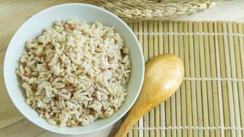 riz brun dans un bol blanc sur une table en bois pour le contenu des aliments santé. photo