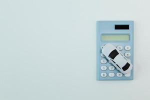 jouet de voiture blanche et calculatrice bleu fond blanc. photo