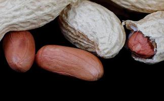 cacahuètes dans la coque et sans elle sur fond noir. photo