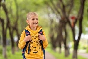 un garçon blond dans un sweat-shirt jaune et un sac à dos sur ses épaules va à l'école photo