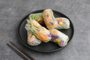 rouleau de printemps aux légumes, salade de rouleaux frais à base de légumes mélangés et de poulet rôti. servi en assiette sur fond de béton foncé. image de mise au point sélective photo