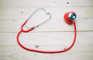 contrôle cardiaque rouge avec instrument médical stéthoscope sur table en bois blanc vue de dessus photo