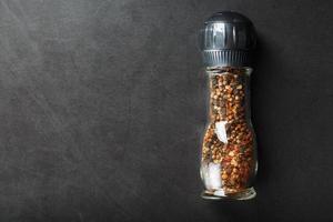 un mélange d'assaisonnements, d'épices et d'herbes dans un moulin à verre sur fond noir. photo