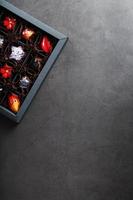 un ensemble de chocolats faits main exclusifs colorés dans une boîte sur fond noir. photo