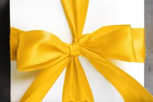 arc jaune sur un cadeau en tissu sur fond blanc. photo