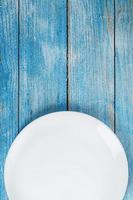 une assiette blanche ronde vide sur une table en bois bleue. photo