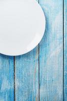 une assiette blanche ronde vide sur une table en bois bleue. photo