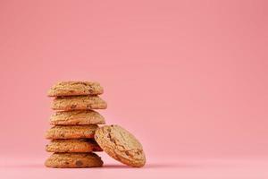 les biscuits à l'avoine avec des morceaux de chocolat se dressent comme une tour sur fond rose photo